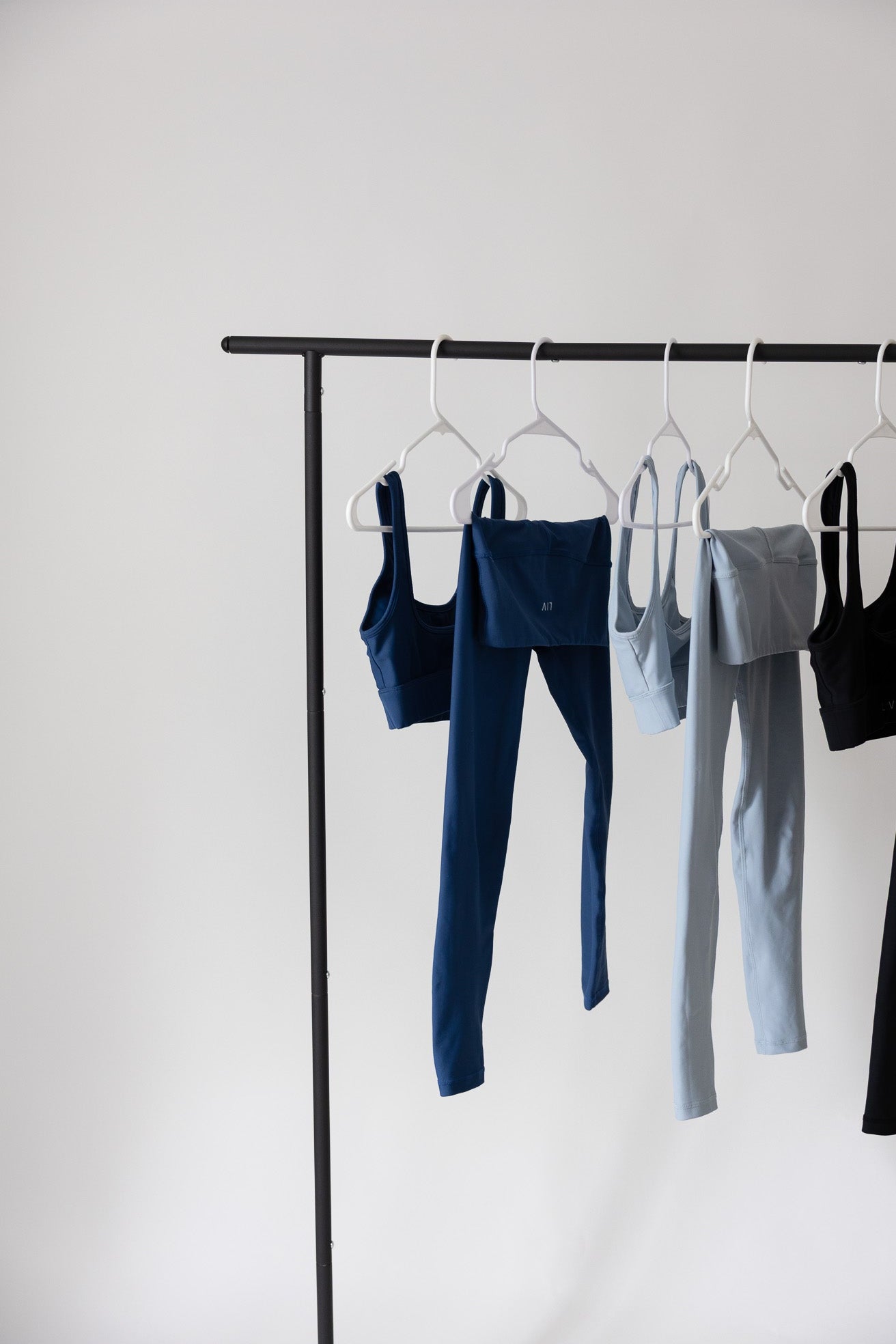 Clothing items hanging on a rack against a white wall